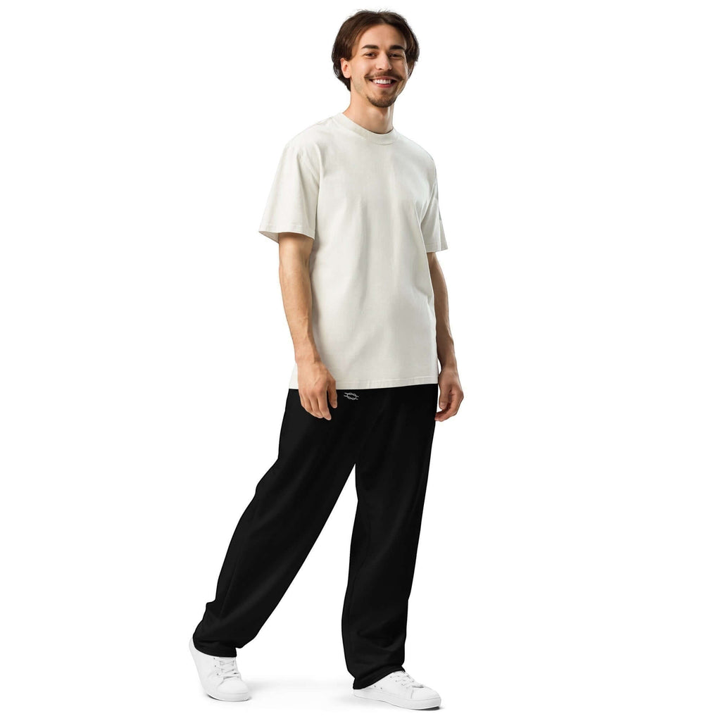 A smiling man wearing Urban Halo black wide-leg joggers and a white t-shirt against a plain white background.